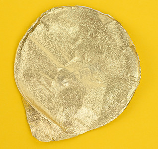 金色圆形摄影照片_黄色背景塑料酸奶罐用圆形金色铝薄盖