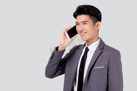 穿着西装的年轻亚洲商人在白色背景下用手机聊天，商人说和听智能手机与对话，男性拿着手机，通信概念。