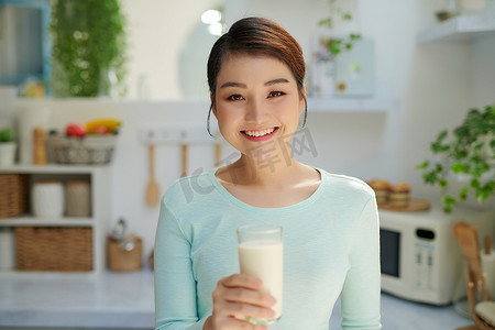 女人喝牛奶看着厨房里的相机