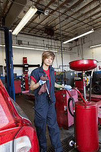 汽车修理店摄影照片_站在焊接设备旁的年轻机械师的画像