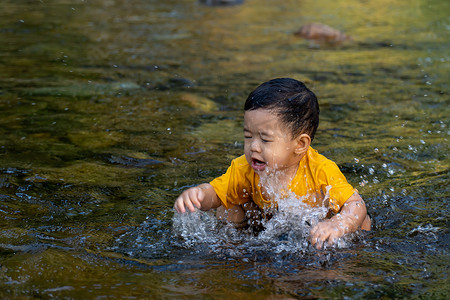 男孩第一次在小溪里玩水，玩得很开心。