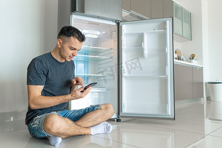 智能冰箱摄影照片_一个年轻人用智能手机点餐。