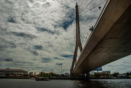 狂暴摄影照片_拉玛八世桥，横跨湄南河的索桥，背景是蓝天的高 V 形塔，阴天
