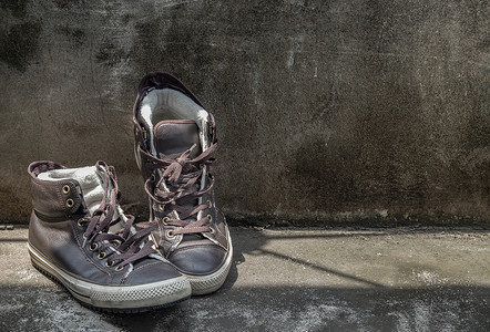 高帮摄影照片_棕色复古高帮帆布运动鞋被放置在旧水泥地板上。