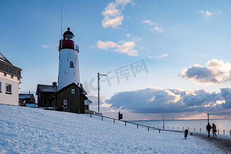 Urk 的冬天，Urk 灯塔旁的堤坝和海滩在冬天被雪覆盖，Urk Flevoland 灯塔旁的日落