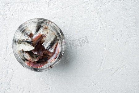 盐渍凤尾鱼片，在玻璃罐中，在白色背景中，顶视图平躺，带有复制空间和文本空间