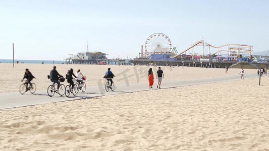 美国加利福尼亚州洛杉矶圣塔莫尼卡 — 2019年10月28日：加州夏季海滩美学，人们在自行车道上行走和骑自行车。