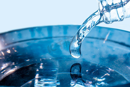 一股流动的蓝水流 一股蓝水从玻璃瓶的颈部涌出 高速拍摄的冷冻水滴 缓慢滴下气泡 冷冻液体飞溅