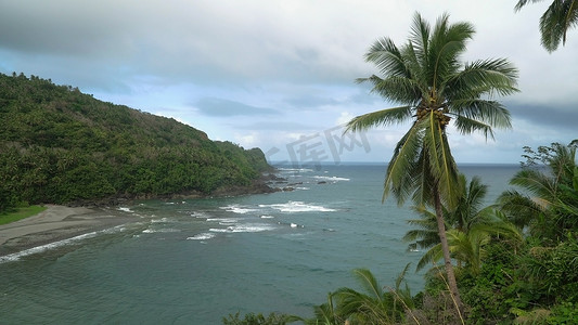 岩石海岛摄影照片_与热带海岛、海滩、岩石和波浪的海景。