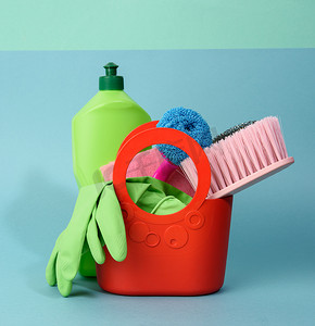 蓝色背景绿色塑料瓶中装有洗涤海绵、橡胶防护手套、刷子和清洁剂的篮子