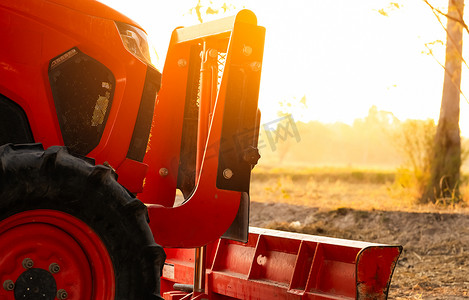 智能拖拉机摄影照片_橙色拖拉机在阳光明媚的夏日早晨停在水稻农场。
