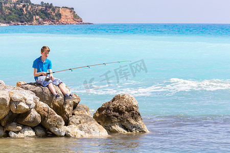 钓竿折断摄影照片_荷兰少年在海边和海滩附近用钓竿钓鱼