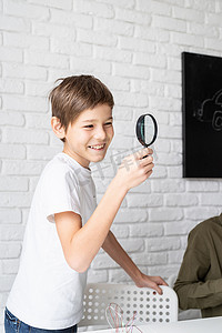男孩使用放大镜在科学项目的实验板上使用 LED 灯