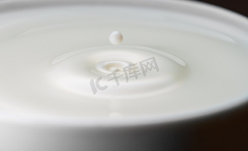 牛奶滴落入装满的杯子中。