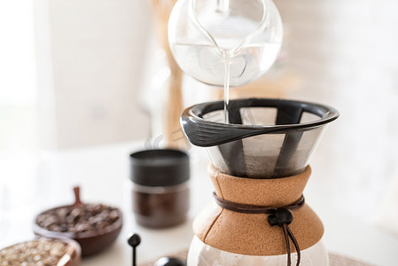 在 chemex 中女性手冲咖啡的特写，将热水倒入过滤器