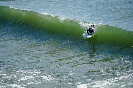 橘子州摄影照片_在美国加利福尼亚州圣地亚哥北部的欧申赛德享受巨浪的男性冲浪者。