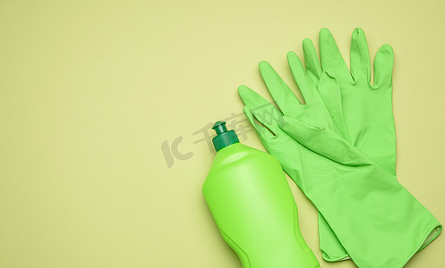 绿色背景塑料瓶中清洁和清洁液用绿色橡胶手套