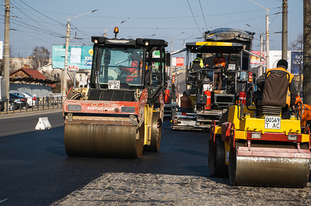 KYIV, UKRAINE - September 10, 2020：带有重型振动压路机的重型沥青压路机在街道上的道路施工现场压上新的热沥青和沥青摊铺机。