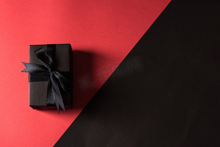 丝带盒摄影照片_在黑纸和黑弓丝带包裹的礼物盒