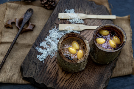 竹节线稿摄影照片_用椰奶 (Khao lam) 煮熟的糯米或在木制的泰国甜点概念上的竹节中烤的糯米。