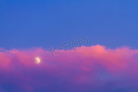 下云朵摄影照片_蓝天下粉红色云朵下的月亮