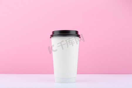 白色桌子上用于茶或咖啡的一次性杯子，带有复制空间的亮紫色背景。