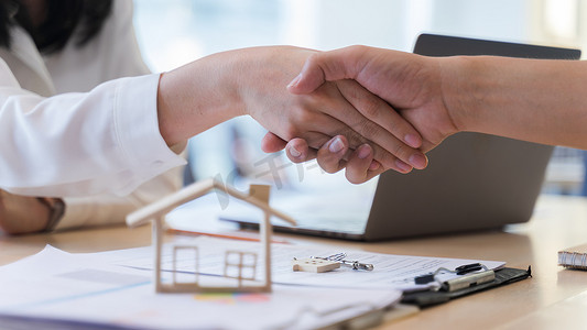女房地产经纪人或卖房人与顾客握手，在讨论成功买房后。
