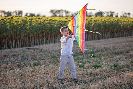 快乐的小男孩手里拿着五颜六色的风筝奔跑