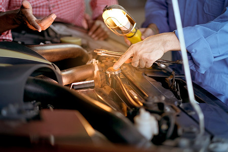 汽车机械师的手有蓝色统一点，并显示汽车散热器盖的问题。
