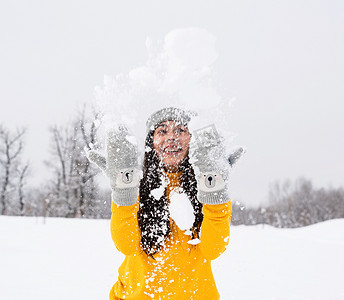 年轻的黑发女人在公园里玩雪