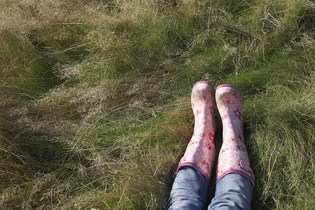 穿着粉红色套鞋躺在草地低处的人