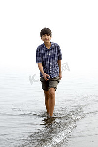 涉水沿海滩的年轻少年男孩