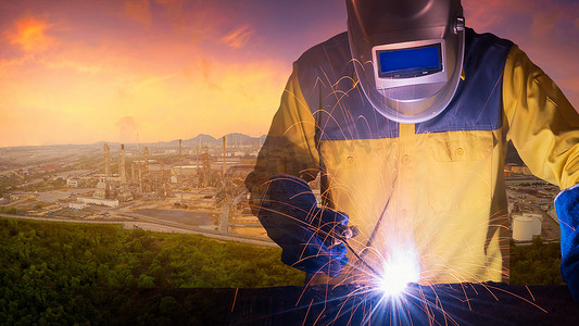 双曝光焊接工人焊接钢结构与石油或石化工业生产的石油和天然气精炼厂的背景。