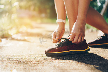 跑鞋速写摄影照片_女人穿跑鞋在自然绿色背景下行走和跑步。健康锻炼。
