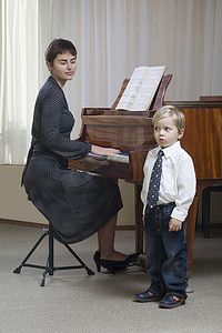 男孩（3-4岁）在老师弹琴的伴奏下唱歌