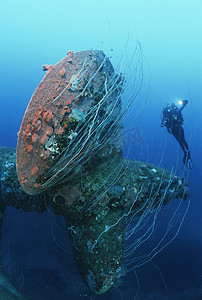 沉没摄影照片_比基尼环礁马绍尔群岛太平洋潜水员在沉没的战舰 HIJMS Nagato 的螺旋桨附近游泳
