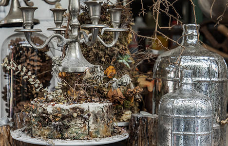 古色古香的烛台和干植物、干花、带玻璃瓶的松果装饰在咖啡馆的木桌上。