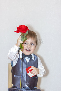 一个小男孩拿着一朵红玫瑰递过来，这是情人节主题的概念。