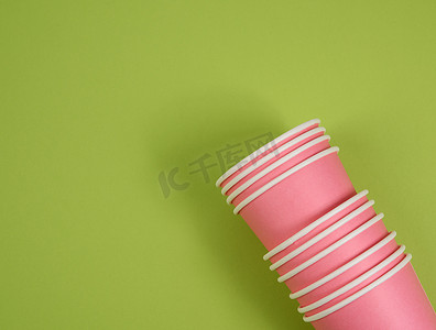 绿色背景中的粉色纸一次性杯子，