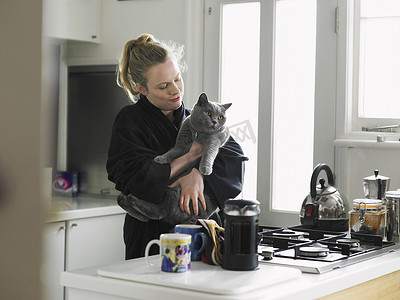 女人抱着猫站在厨房里