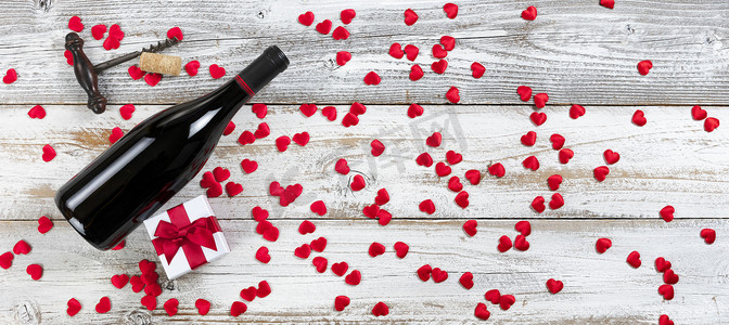 爱心礼盒红色摄影照片_满瓶红酒，带礼盒，白色质朴天然木材上的红色可爱心，采用剥皮组合，适合情人节概念