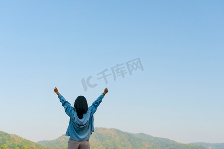 蓝天夏日山背景下的女性举起手来迎接天空自由概念