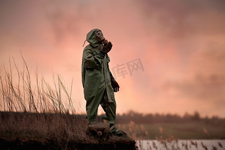 一个戴着防毒面具和防护服的男人站在深渊的边缘。