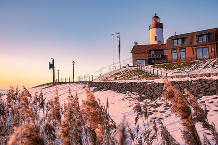 Urk 的冬天，Urk 灯塔旁的堤坝和海滩在冬天被雪覆盖，Urk Flevoland 灯塔旁的日落