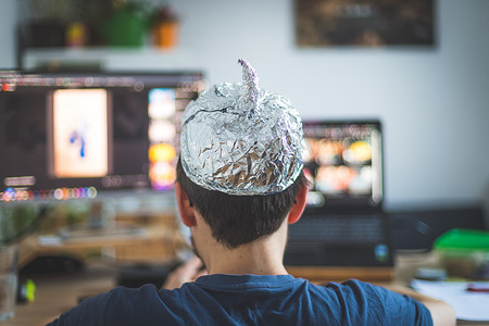 阴谋论概念：年轻人头戴铝头，坐在电脑前看视频