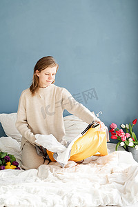 坐在家里床上整理衣服的年轻女人