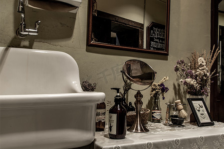复古浴室内部配有洗白盆、梳妆台、洗手液瓶、镜子和干花。