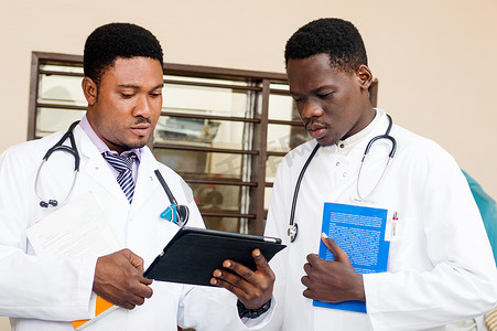 两位常务医生在办公室共享一台数字平板电脑。