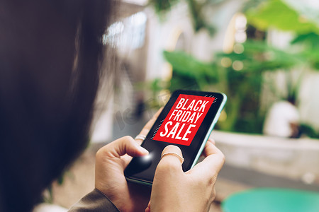 使用智能手机的女性在黑色星期五销售网上销售，供网上购物的人使用聊天框、购物车、美元图标弹出。
