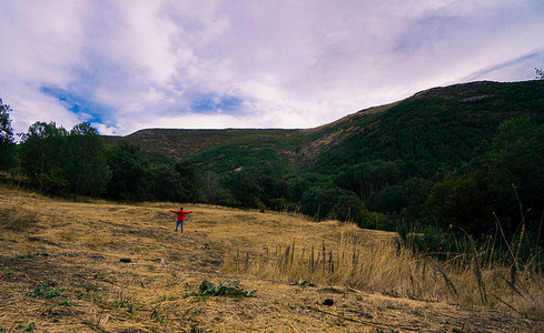 群山环绕的干草甸和背景中的一个人